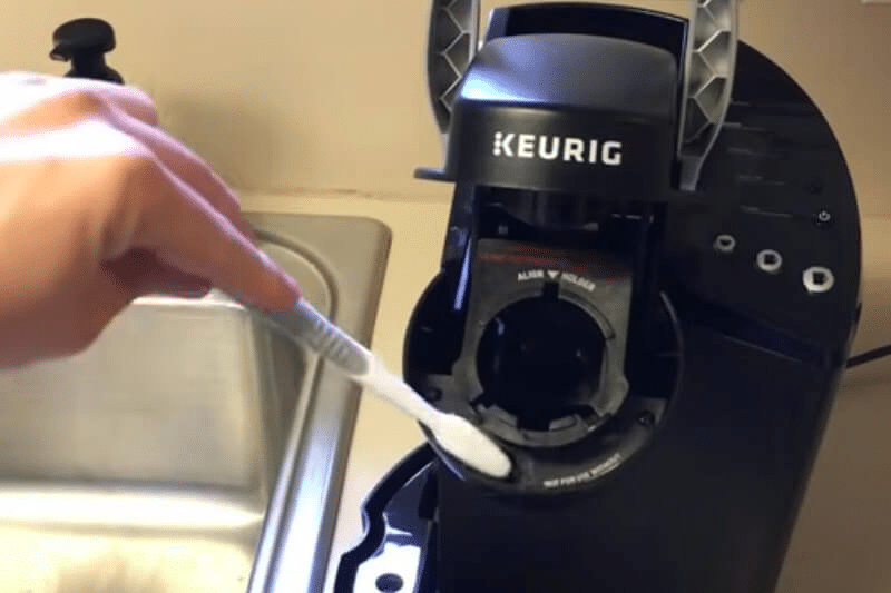 Using a soft brush to clean the K-cup holder of keurig